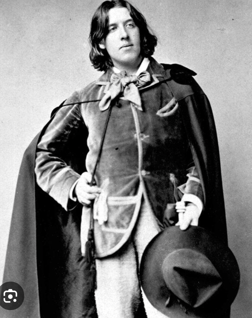 Oscar Wilde during his 1882 America tour, in velvet coat and cape, holding a wide-brimmed hat